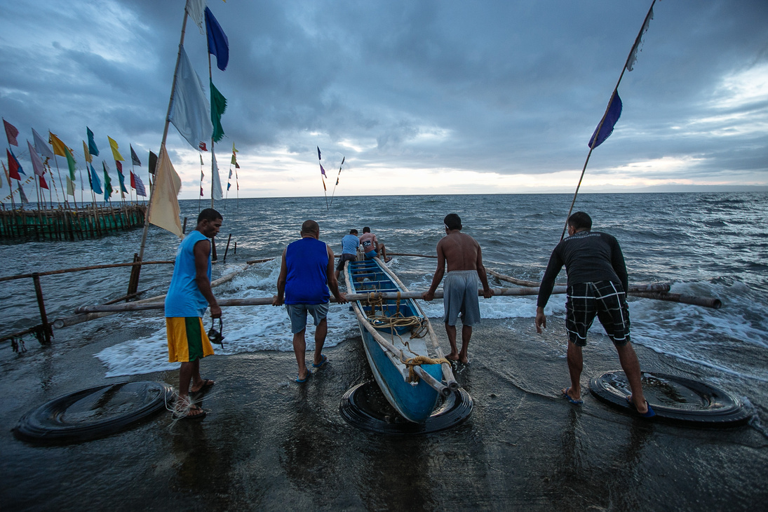 Four Person Pushing Boat Off Shore